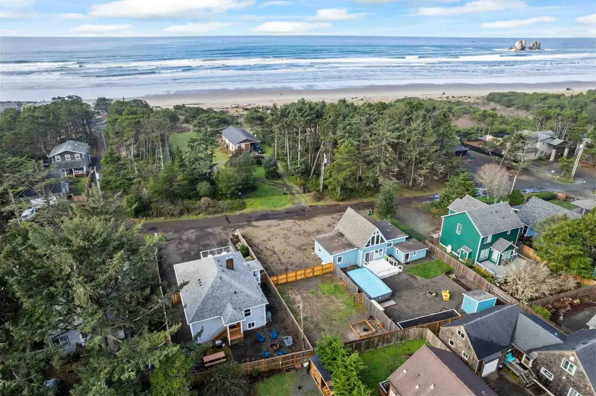 An elevated view featuring the ocean, a line of houses, lush trees, and a swimming pool. The scene suggests a family-friendly area with amenities and spaces for gatherings, while the ocean backdrop reinforces the coastal adventure theme.