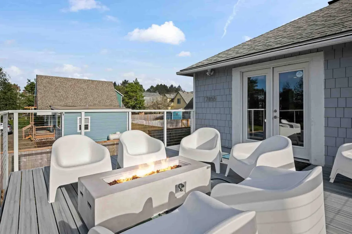 An inviting exterior scene featuring a fire pit surrounded by comfortable seating and a deck railing, ideal for socializing or unwinding after a day of exploration. The setting exudes a casual and welcoming vibe with open views, encouraging group gatherings in the fresh air.