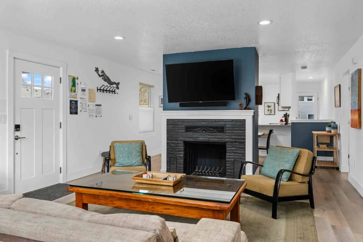 A secondary living area with a fireplace, mounted television, coffee table, and comfortable chairs arranged for conversation or viewing. The ambiance is warm and inviting, offering a slightly different angle and décor from the main living room.